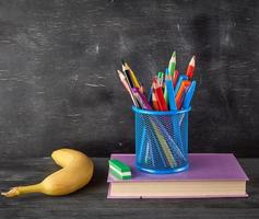 yellow banana, blue stationery glass with multi-colored wooden pencils photo