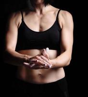 girl with a sports figure dressed in a black top claps in her hands with white magnesia photo