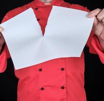 chef con uniforme rojo sosteniendo una sábana blanca en blanco y rasgándola por la mitad foto