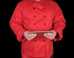 chef con uniforme rojo sosteniendo una tableta electrónica en sus manos foto