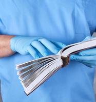 doctor in blue uniform holds an open book in his hands photo