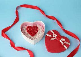red heart-shaped gift box with a bow on a blue background photo
