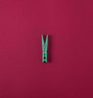 Green plastic clothes pin on a red background photo
