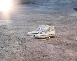 pair of very old white sneakers with untied laces photo