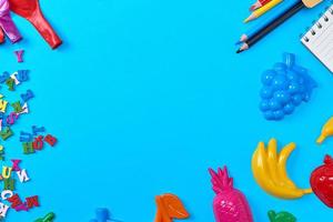 Blue background with childrens plastic toys, pencils photo