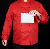 chef en uniforme rojo sosteniendo un cuaderno en blanco foto