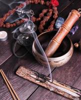 copper singing bowl and a wooden stick on a brown table photo