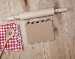 cuaderno abierto en blanco en línea y accesorios de cocina de madera foto