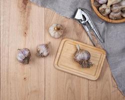 unpeeled fresh garlic fruits and iron hand press photo