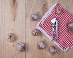 frutos de ajo frescos sin pelar y una prensa de hierro foto