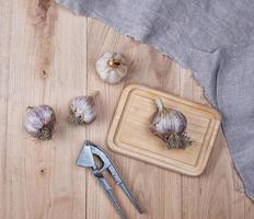 unpeeled fresh garlic fruits and iron hand press photo
