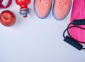 pink sports sneakers and a red water bottle, black jump rope photo