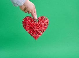 female hand holding red wicker decorative heart photo