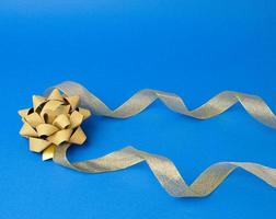 Shiny golden satin ribbon on a blue background photo