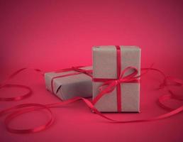 box wrapped in brown kraft paper and tied with a red thin silk ribbon on a red background photo