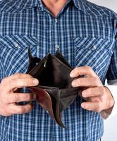 man in blue plaid shirt holds open empty leather wallet photo