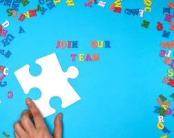 hand hold two large white puzzles and the inscription join our team on a blue background photo