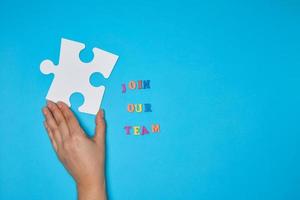 women's hand hold  large white puzzle and the inscription join our team photo