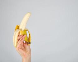 peeled fresh banana in female hand photo