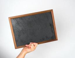 hand holding an empty wooden chalk frame on a gray background photo