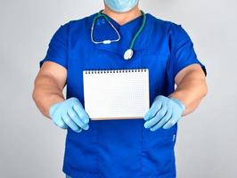 doctor in blue uniform and sterile latex gloves holding open blank notebook photo