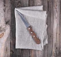 old kitchen knife on a gray napkin, wooden background photo