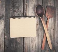 open empty notebook and two wooden spoons on a gray background photo