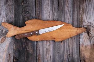old wooden board in the form of a fish figure and a knife photo