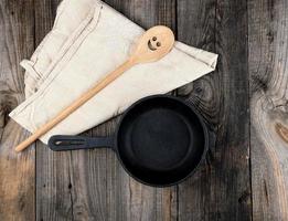 empty black round frying pan with  handle and spoon photo