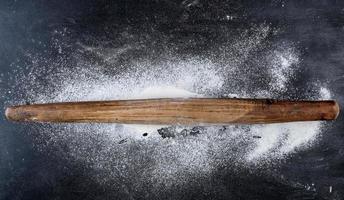 wooden rolling pin on a black background, top view photo