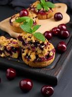 Portion crumble pie with cherries on a wooden board decorated with green mint leaves photo