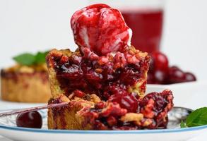 Cherry crumble pie decorated with a scoop of ice cream and drizzled with cherry sauce photo