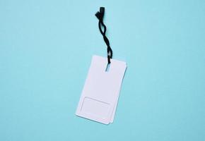 Blank rectangular paper white price tag with black rope on a blue background photo