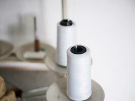The white thread of the sewing machine that is being installed in the machine for sewing. White thread spool photo