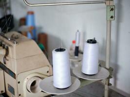 The white thread of the sewing machine that is being installed in the machine for sewing. White thread spool photo