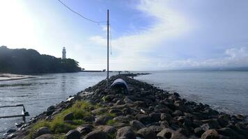 The coastal rocks are piled up into a road between the sea and the river, the port, the beach and the sky blue photo