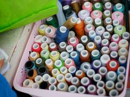 Multicolor sewing threads on wooden background.Color sewing threads on white background, top view photo