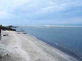 View of the shoreline from above, white waves, beach sand, clear water and rocks. Panoramic view. Beautiful beaches photo