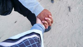 A couple walking holding hands on the beach with a background of beach sand photo