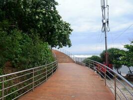 Road or bridge or wooden stairs on the beach , View of the beach bridge in Sayang Heulang Indonesia photo