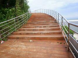 Road or bridge or wooden stairs on the beach , View of the beach bridge in Sayang Heulang Indonesia photo