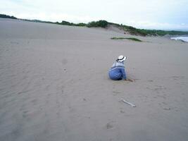 Back of the woman in the hat who was sitting and playing beach sand, the view of the sand photo