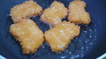 o processo de fritar os nuggets em uma frigideira com pouco óleo. a cor das pepitas é ouro acastanhado, indicando que as pepitas estão cozidas. video