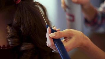 Young blonde stylist girl makes hairstyle to a woman in hair studio video