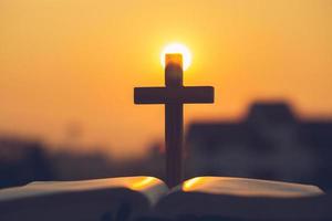 Silhouette of the cross  on the holy bible, religion symbol in light and landscape over a sunrise, background, religious, faith concept photo