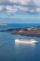 Cruise ship in the sea near the volcano of Santorini island, Greece. Beautiful tourism and travel background, transportation concept, summer vacation scenery. Sea transfer in Santorini photo