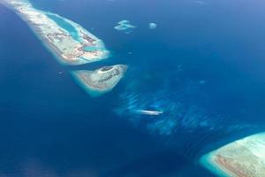 Aerial view of Maldives islands and atolls. Maldives tourism and travel background. Amazing blue sea, coral reef and atoll drone view. Beautiful nature landscape, seascape, exotic destination photo