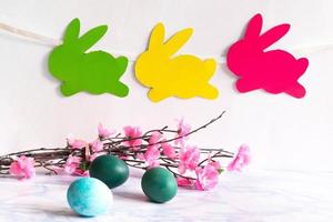 Colorful eggs with willow and handmade bunny easter garland on netural background. photo