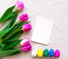 Happy ester. color eggs with tulips on background top view photo