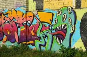 Fragmento colorido abstracto de pinturas de graffiti en la pared de ladrillo antiguo con cara de pulpo aterrador. composición de arte callejero con partes de letras no escritas y personajes de dibujos animados foto